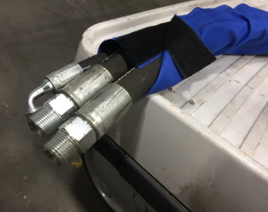 Blue hook-and-loop sleeve wrapped around hydraulic hoses