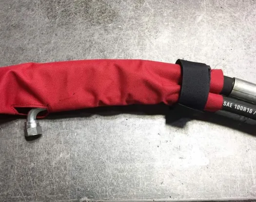 Red sleeve on a hydraulic hose, closed at the end with a hook-and-loop strap