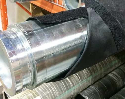 Black hook-and-loop sleeve wrapped around a large metal pipe