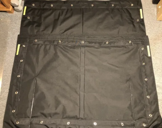 Two-piece windshield cover laid flat, showing grommets