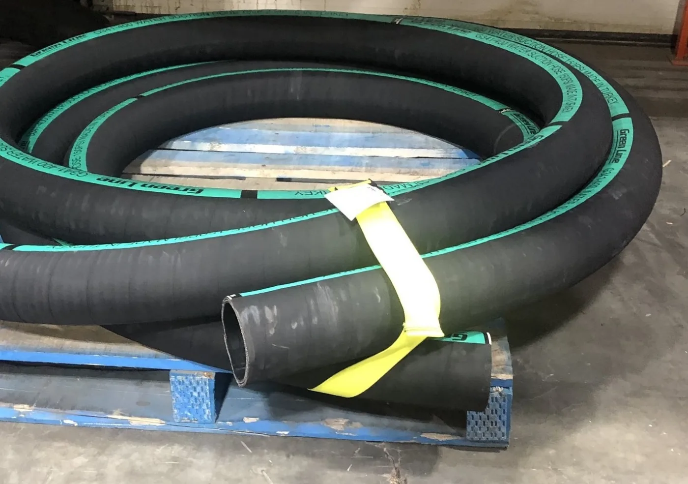 Yellow bundling strap around a coil of hose on a pallet