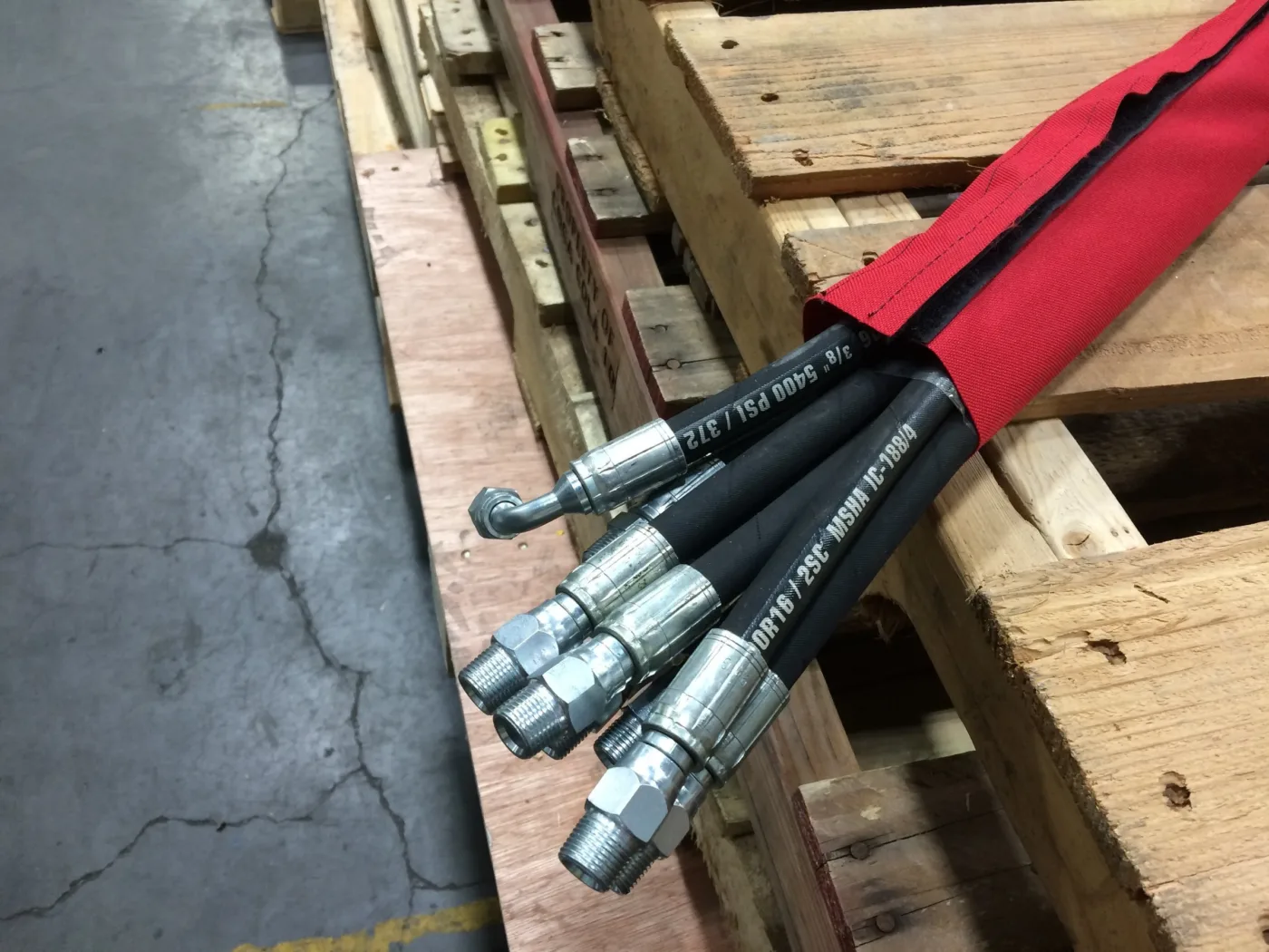 Red protective sleeve bundling hydraulic hoses