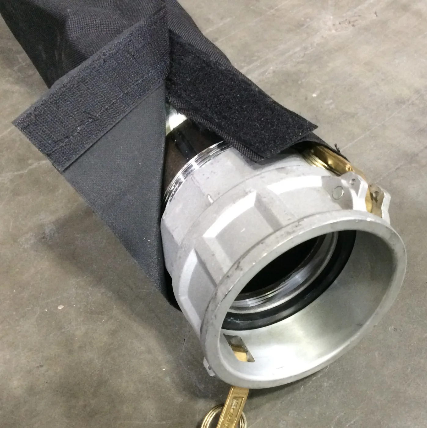 Black hook-and-loop sleeve fitted over a large coupling