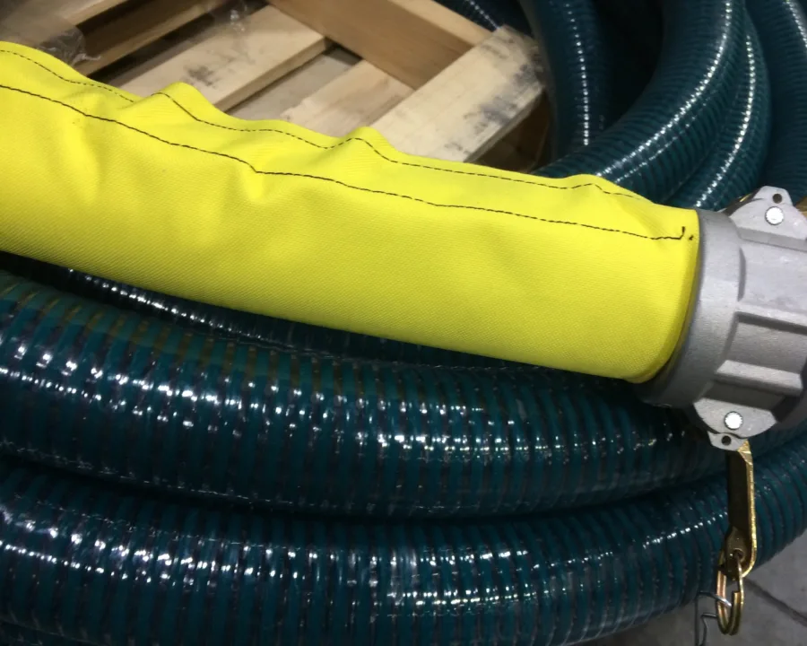 Yellow protective sleeve over a suction hose with a cam-lock coupling