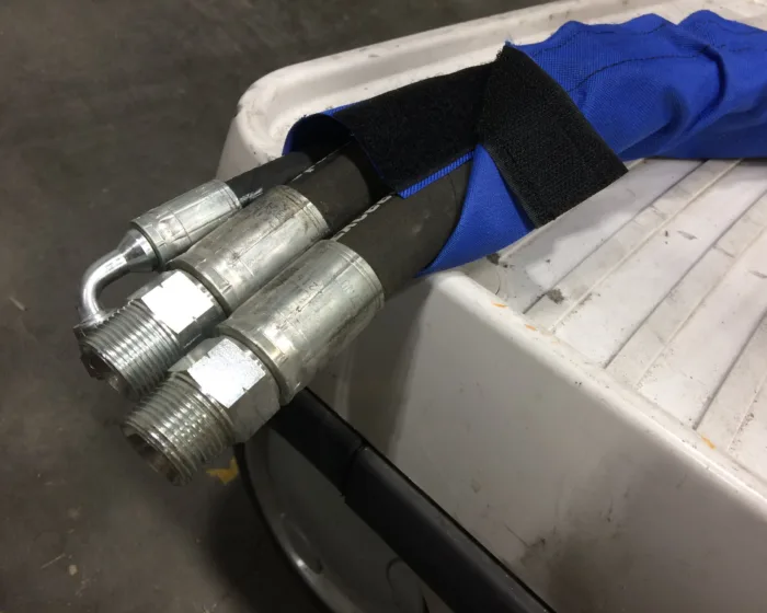 Blue hook-and-loop sleeve wrapped around hydraulic hoses