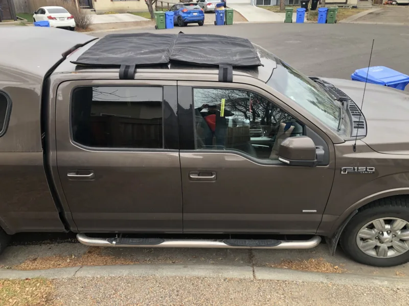 Sunroof hail cover strapped to the roof of a pickup truck