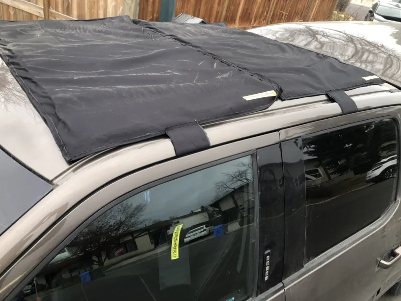 Sunroof hail cover held on a pickup roof by its straps