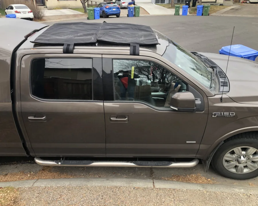 Sunroof hail cover strapped to the roof of a pickup truck