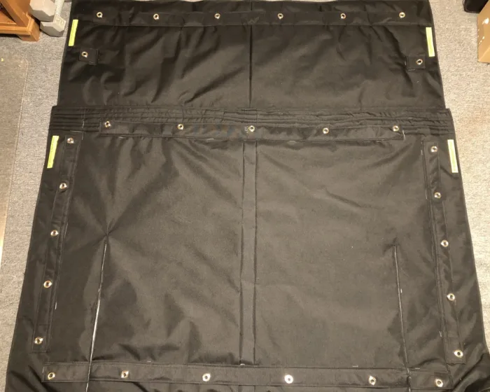 Two-piece windshield cover laid flat, showing grommets